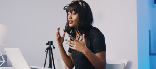 A woman gestures while talking to someone on a video call on her laptop