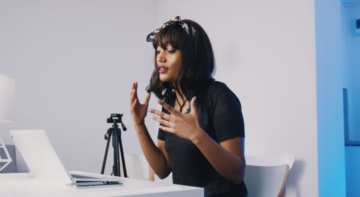 A woman gestures while talking to someone on a video call on her laptop