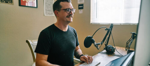 A man with a home recording studio smiles as he works on his computer
