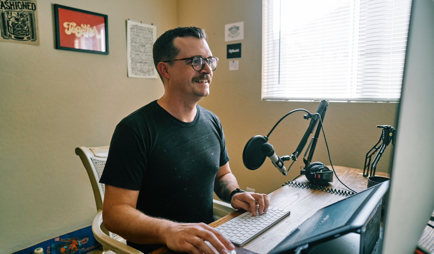 A man with a home recording studio smiles as he works on his computer