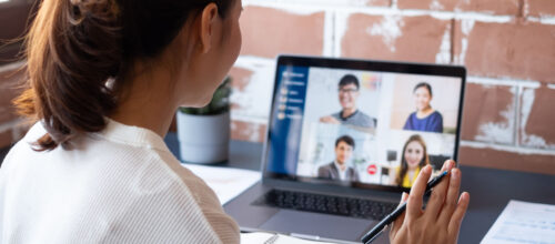A woman raises her hand while participating in a group video call