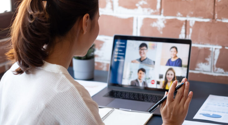 A woman raises her hand while participating in a group video call