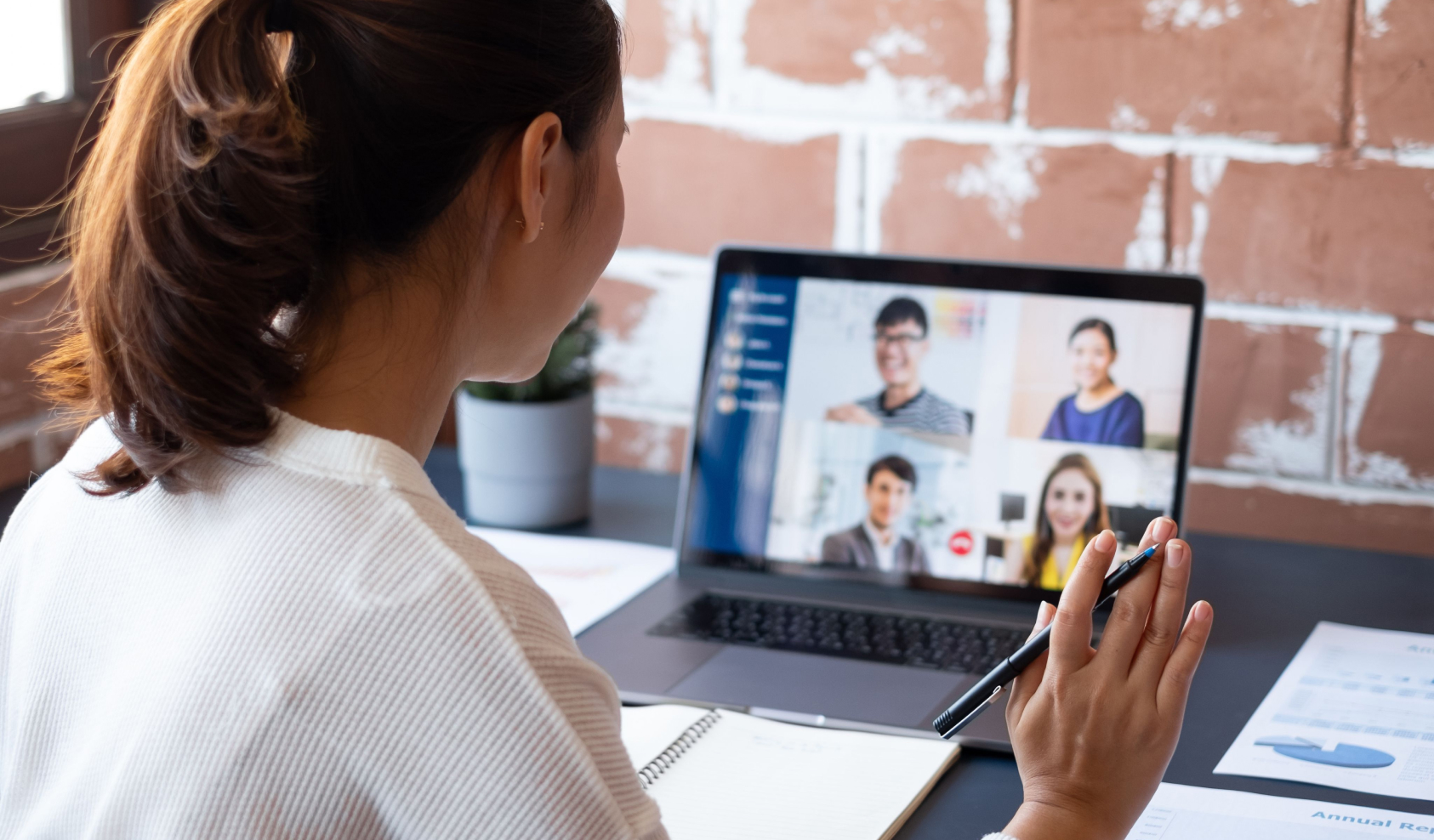 A woman raises her hand while participating in a group video call