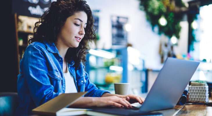 A woman types on her laptop
