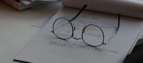 A pair of glasses rest on a sheet of paper with a flow chart written on it