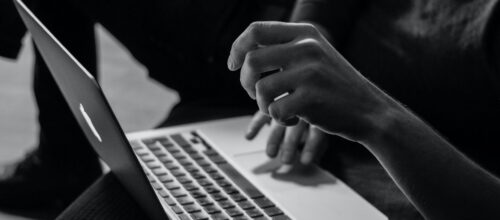 A black and white image of a person using a laptop