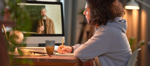 A student watches an online lecture and takes notes