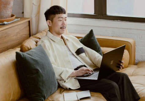 A man sits on a couch and uses a laptop