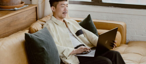 A man sits on a couch and uses a laptop
