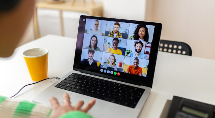 A laptop screen shows a grid view of video call participants