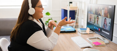 A woman participating in a video call gestures to her colleagues on the call