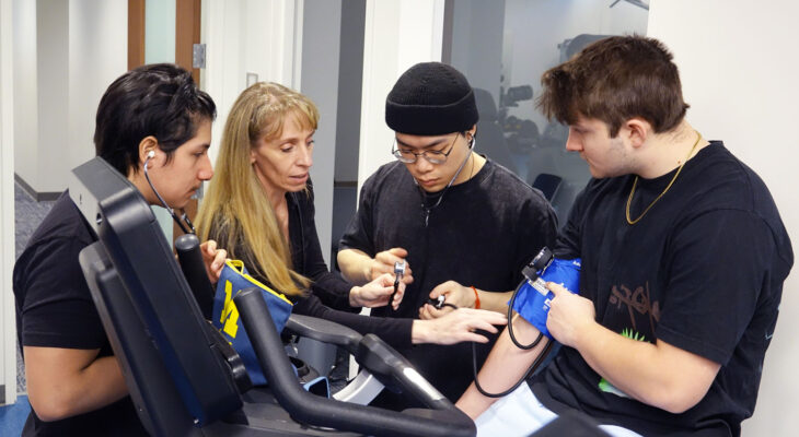 Students practice taking blood pressure under supervision during a kinesiology lab at the University of Michigan.